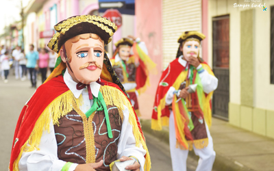 Actores enmascarados con trajes y sombreros tradicionales actuando en una calle durante la fiesta de San Sebastián en Diriamba